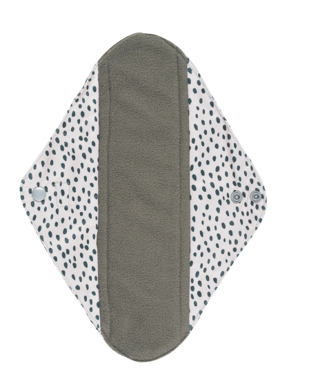 Inside of a reusable Sanitary Pad with a white background and black spotty design on it and showing the black absorbent inner.