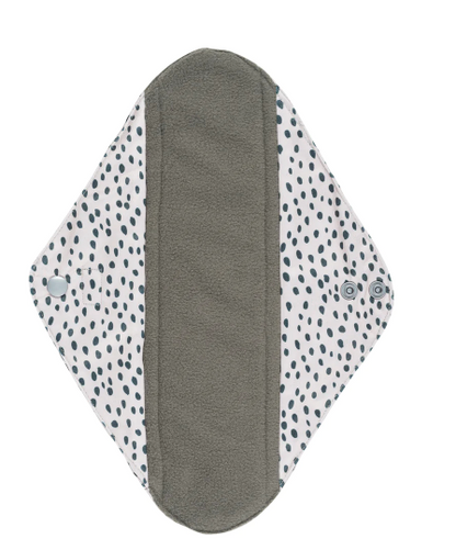 Inside of a reusable Sanitary Pad with a white background and black spotty design on it and showing the black absorbent inner.
