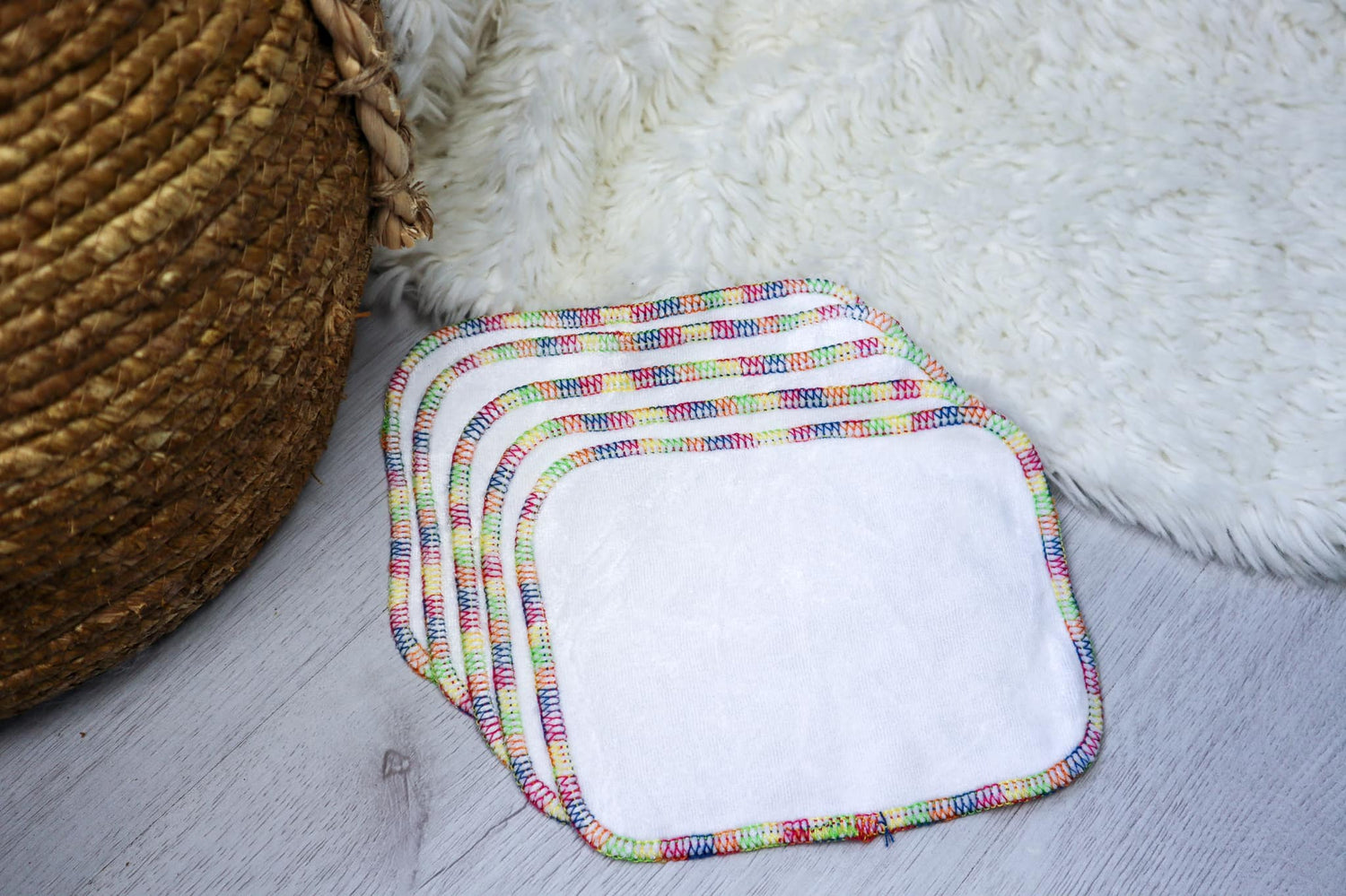 Image showing 5 reusable cloth wipes with a rainbow trim. 